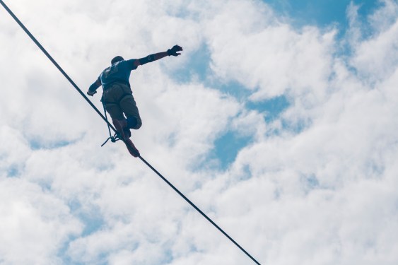 Low Angle View Of Man With Arms Outstretched Walking On Tightrope Against Cloudy Sky, used in a post about edtech Saasguru