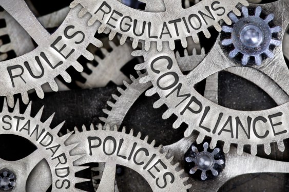Macro photo of tooth wheels with COMPLIANCE, REGULATIONS, STANDARDS, POLICIES and RULES words imprinted on metal surface, used in a post about Australian regtech FrankieOne