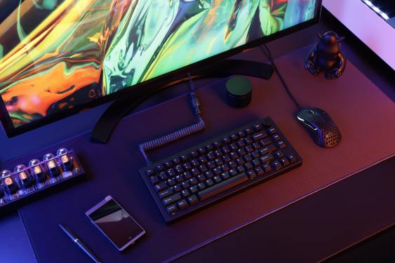 A Drop mechanical keyboard on a desk in front of a monitor