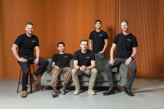 five men in black t shirts pose around a couch