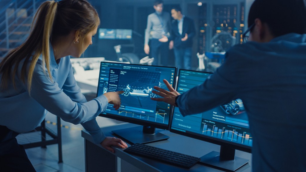 Man and woman engineers in front of a dual screen display designing an electric car.
