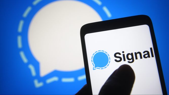a Signal logo is seen on a smartphone screen.