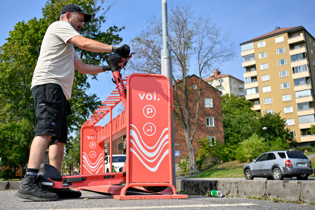 A fleet specialist at Voi Technology AB replaces public hire electric scooters at a designated parking area in Stockholm, Sweden.