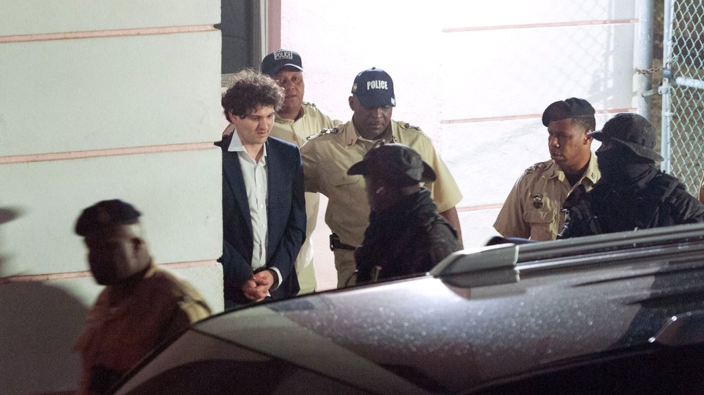 FTX founder Sam Bankman-Fried (2nd L) is led away handcuffed by officers of the Royal Bahamas Police Force in Nassau, Bahamas on December 13, 2022. - Disgraced cryptocurrency tycoon Sam Bankman-Fried was hit with multiple criminal charges December 13, 2022, accused of committing one of the biggest financial frauds in US history. Bankman-Fried will serve time at The Bahamas Department of Corrections until February 8, 2023. (Photo by Mario DUNCANSON / AFP) (Photo by MARIO DUNCANSON/AFP via Getty Images)