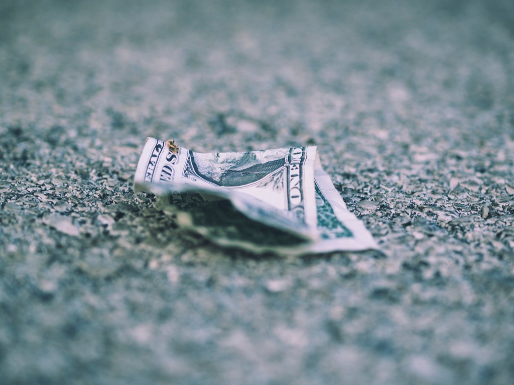 Old dollar bill crumpled on road