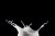 Image of a glass of milk splashing against a black background.