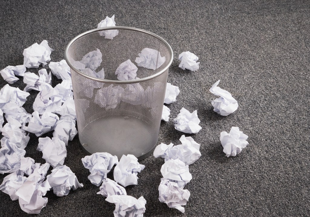 Discarded paper on floor around wastebasket