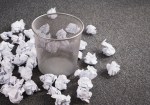 Discarded paper on floor around wastebasket