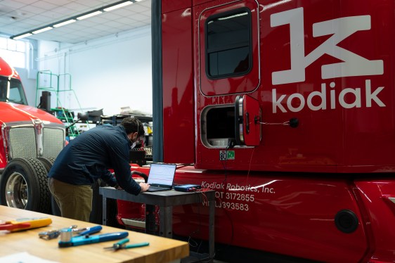 man in front of laptop near cabin of truck, painted red with Kodiak logo