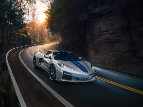 Chevrolet Corvette E-Ray 3LZ convertible in Silver Flare with Electric Blue stripe package driving on a curved mountain road.