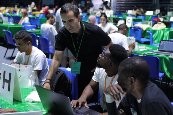 man standing over a table of people coding