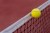 Tennis ball hitting the net on red court.