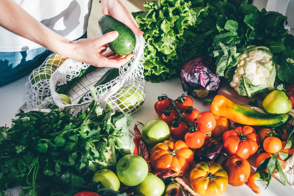 Image of a person pulling fresh vegetables out of a mesh bag.