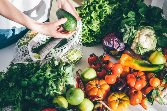 Image of a person pulling fresh vegetables out of a mesh bag.