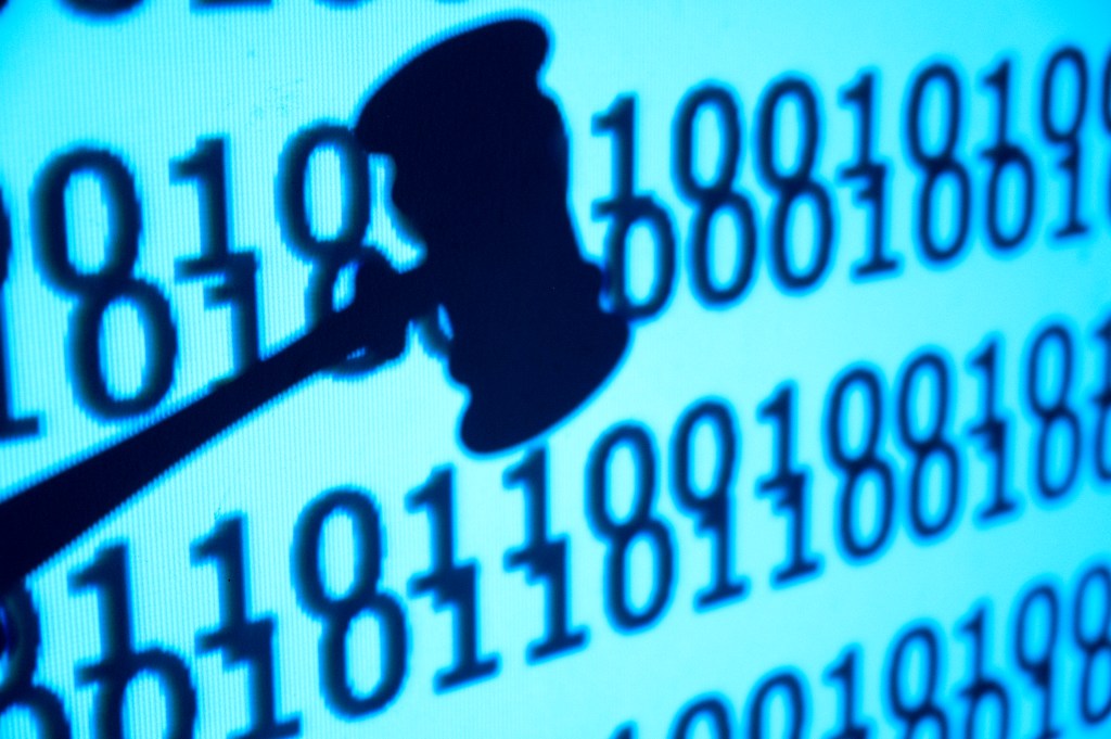 An image of a close up gavel in front of code, concept of justice and lawsuit