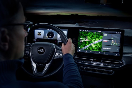man's hands hold a steering wheel with driver monitoring system active on screen