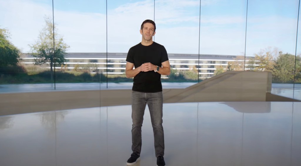 man standing, on stage, Apple HQ in background