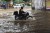 Swiggy worker riding motorcycle on a flooded street