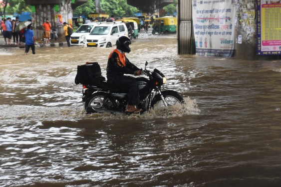 Swiggy worker riding motorcycle on a flooded street