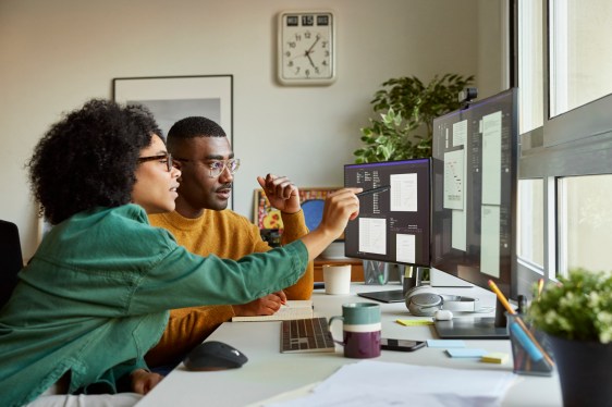 Two business people looking at computer screen with data about the health of the business.