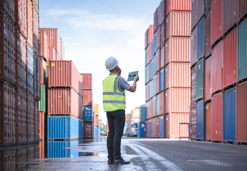 Engineer with tablet at Containers yard from Cargo freight ship for import export, used in a post about Freightify