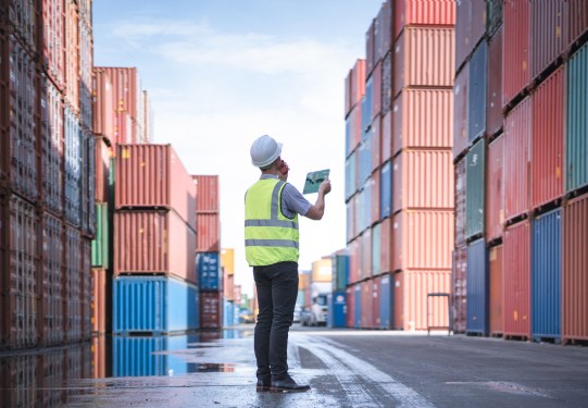 Engineer with tablet at Containers yard from Cargo freight ship for import export, used in a post about Freightify