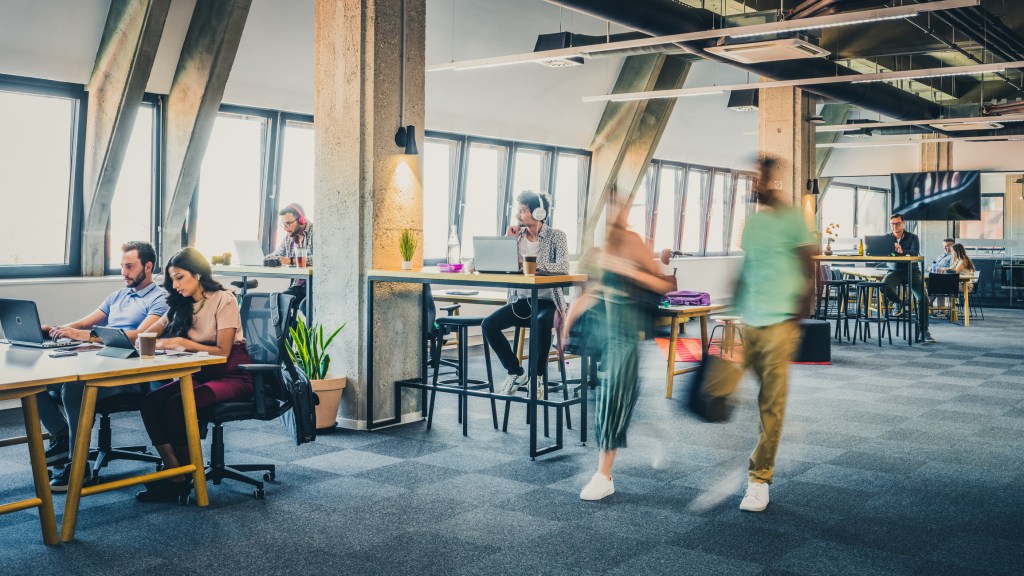 Blurred motion of two coworkers coming to work while the rest are already working.