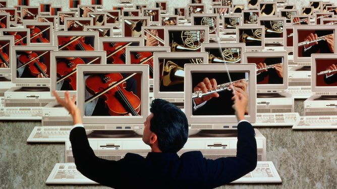 Conductor in front of 'orchestra' of computer screens, depicting 'microservices orchestration'