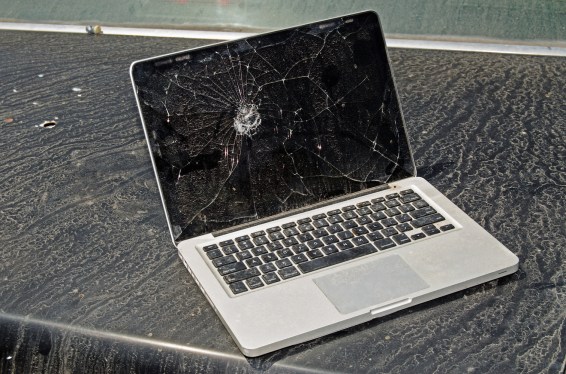 Broken, dirty and abandoned laptop with cracked screen. Laptop looks like it has been left outdoors in the elements for quite some time.