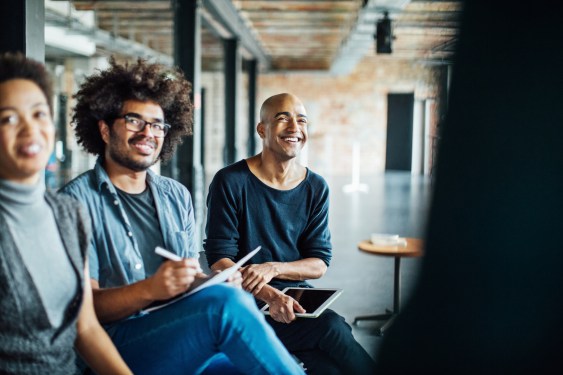 Smiling colleagues, seated, listening in meeting