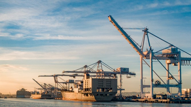 Oakland Harbor with shipping cranes at sunset