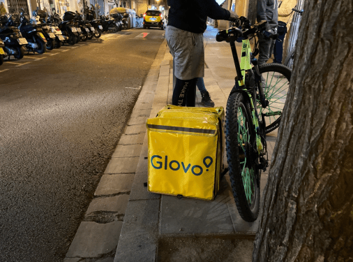 Glovo rider standing next to a bike