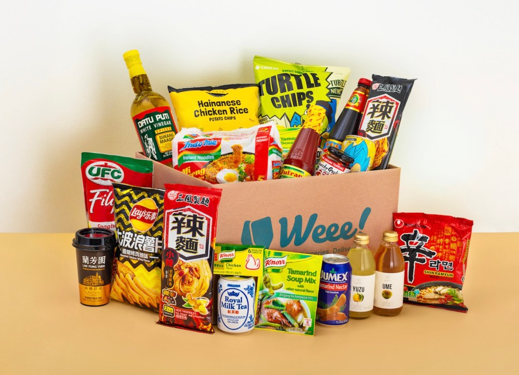 an assortment of foods and grocery goods on a table with a Weee! box on display