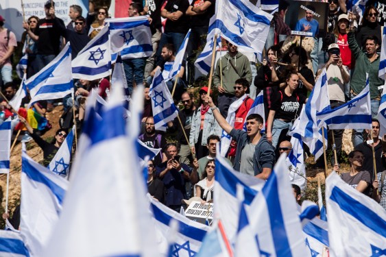 Protestors wave flags as thousands of Israelis attend a rally against Israeli Government's judicial overhaul plan on March 27, 2023