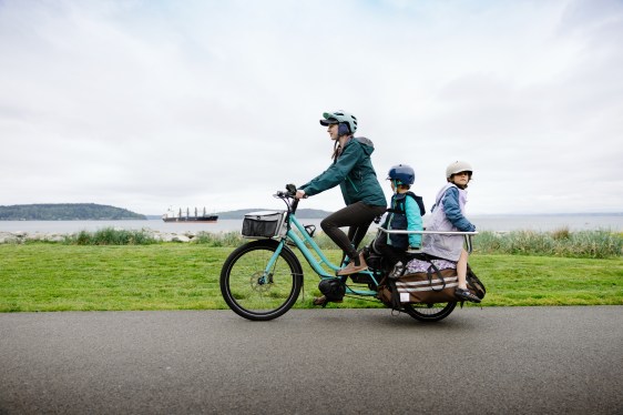 A family biking on a large electric powered cargo bicycle.
