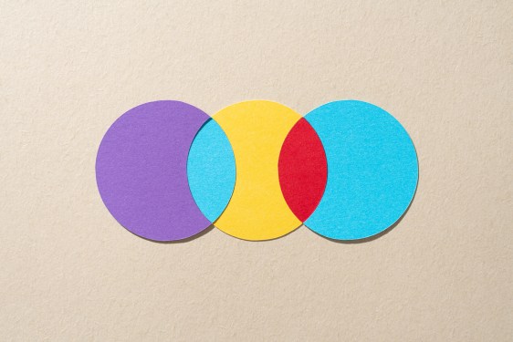Paper Craft Multi Colored Venn Chart Composed of Three Crossing Circles on Beige Background Directly Above View.