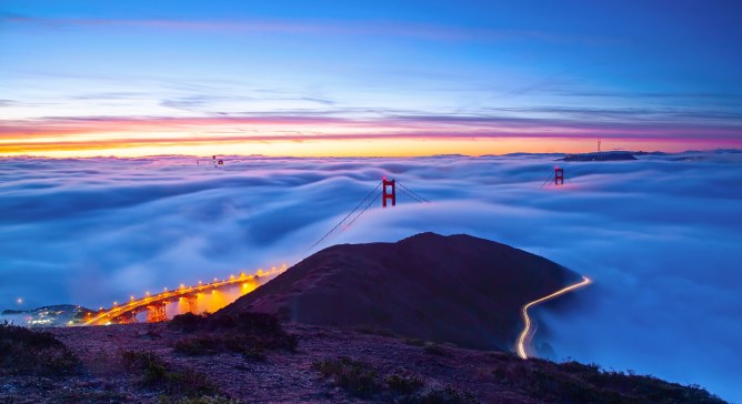 The sunset sky over the Golden Gate Bridge barely seen from dense clouds in the evening in summer