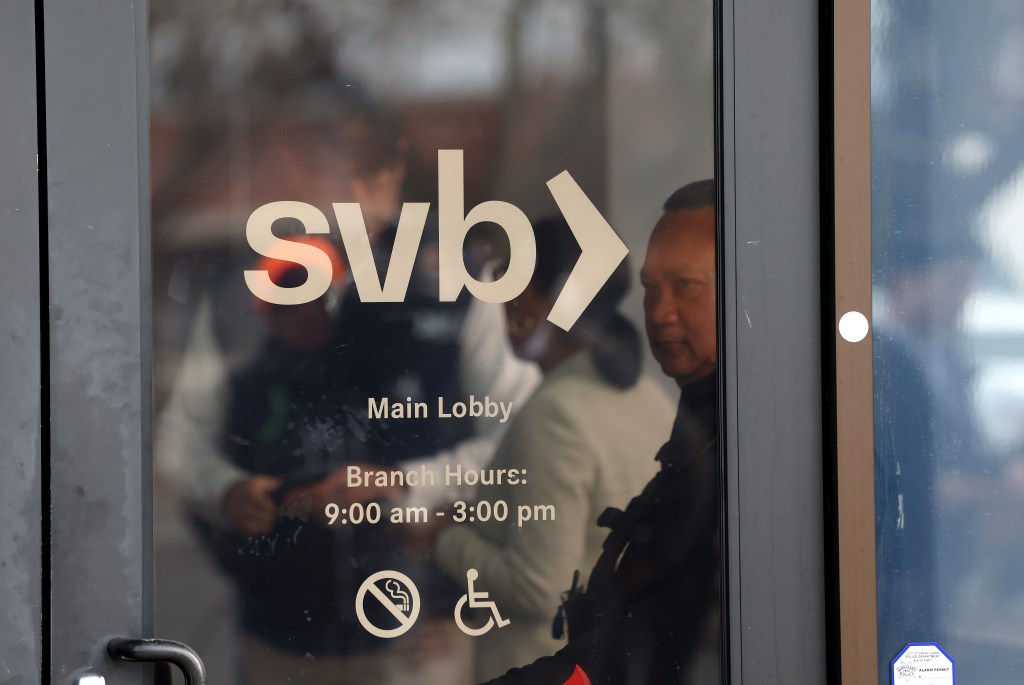 A security guard at Silicon Valley Bank monitors a line of people outside the office on March 13, 2023 in Santa Clara, California