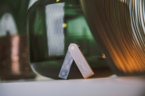 A photo of a Ledger Crypto Wallet in front of some abstract objects