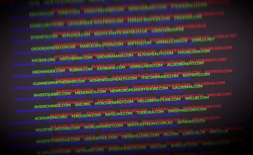 a manipulated photo of the Clop ransomware leaks page, displaying domains targeting by ransomware on a multi-colored blurry text