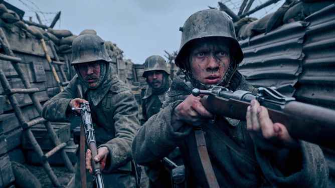 WWI German soldiers in a trench, rifles raised. Scene from All Quiet on the Western Front from Netflix