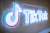 TikTok's neon logo and music note symbol on a concrete wall