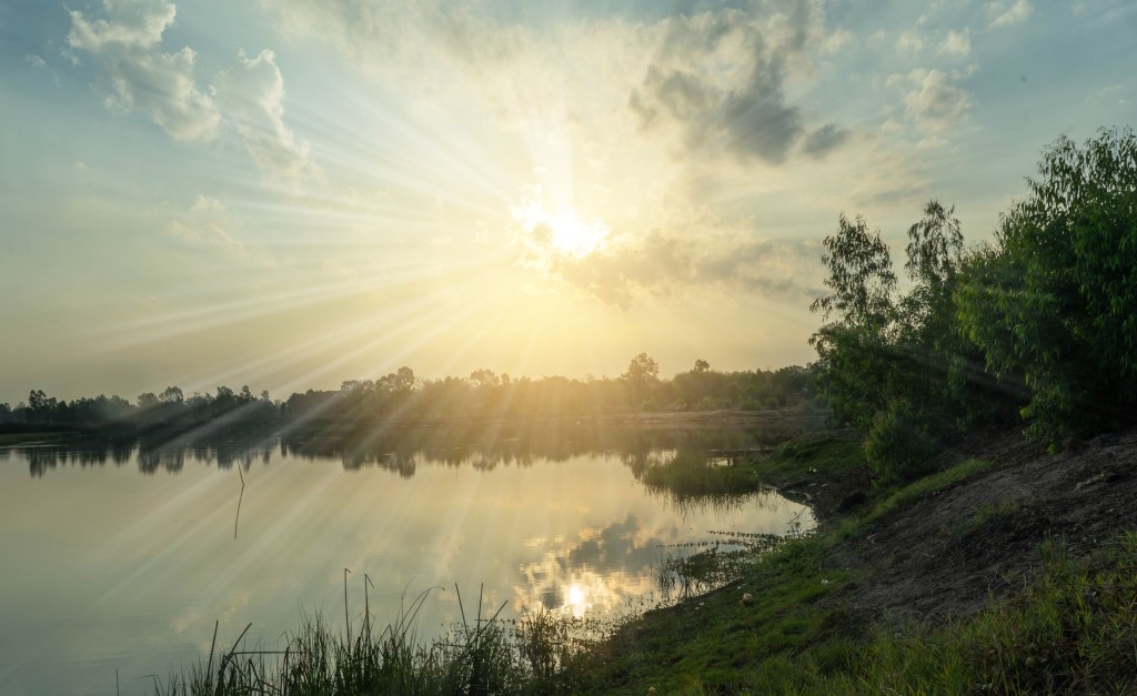 Bright sunshine through clouds over water.