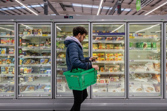 Man standing in front of refrigerator cases at a supermarket.