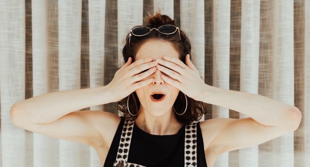 woman standing with hands covering her eyes