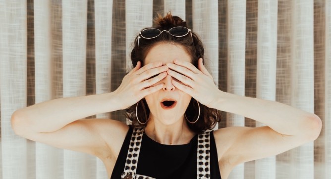 woman standing with hands covering her eyes