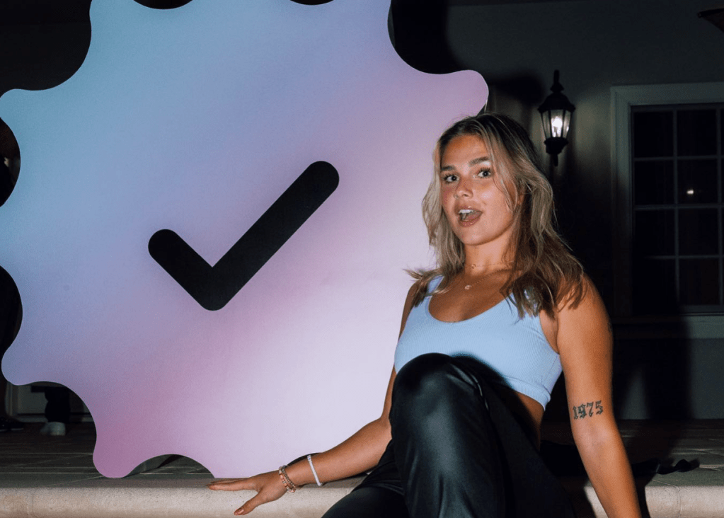 Fanfix; young woman standing in front of large checkmark