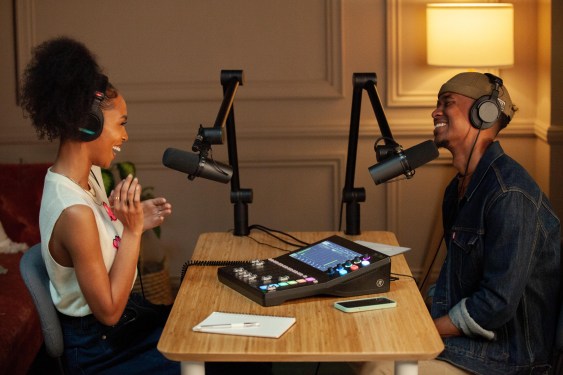 two people facing each other, seated at a desk, speaking into mics