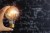 Light bulb in a person's hand in front of a blackboard with equations written on it.