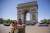 Tourists take selfie pictures in front of the Arc de Triomphe in Paris.
